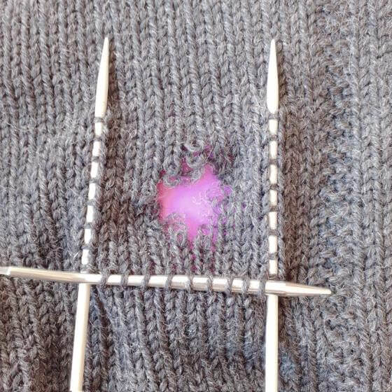 Plocka upp maskor längs ett varv genom att stoppa in stickan i den högra maskbågen på maskans V.